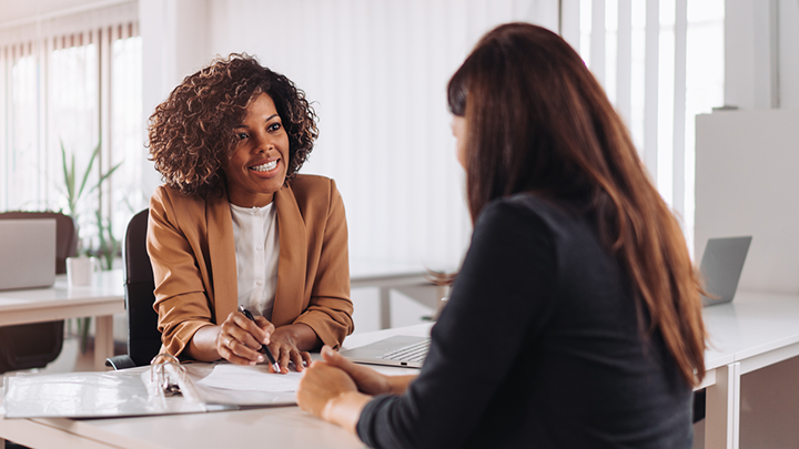 Two business professionals engaging in a consultation, with one taking notes, indicative of a business valuation discussion.