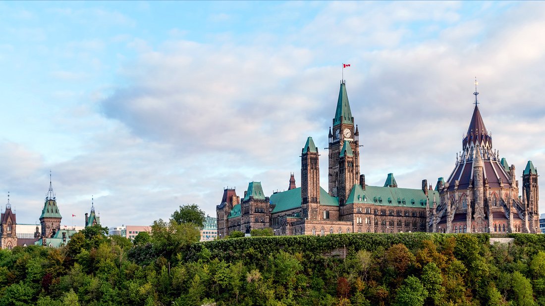 A landscape shot of the Canadian Parliament building in Ottawa, with an evening blue sky in the background.