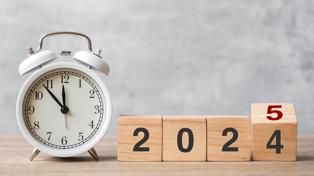 An alarm clock showing five minutes to midnight alongside wooden blocks transitioning from 2024 to 2025, symbolizing year-end tax planning.