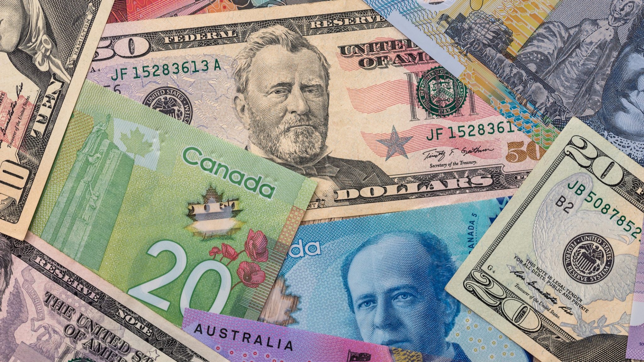 A close-up of multiple international currency notes, including Canadian and U.S. dollars, representing global currency exchange.