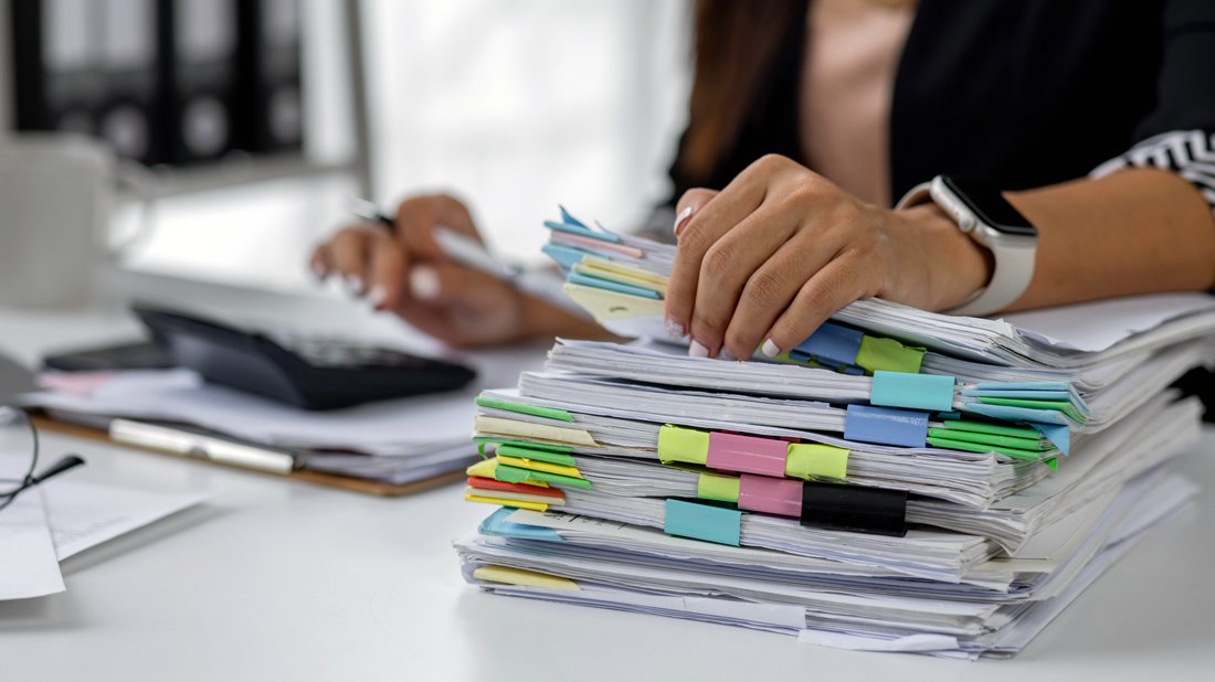 Person organizing a stack of colour-coded documents after tax season.